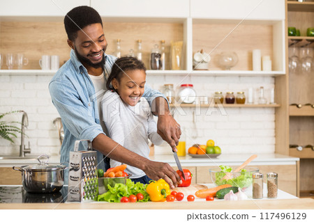 A black father teaches his daughter kitchen skills, celebrating family and fatherhood while preparing a healthy meal together A black father teaches his daughter kitchen skills, celebrating family and fatherhood while preparing a healthy meal together 117496129