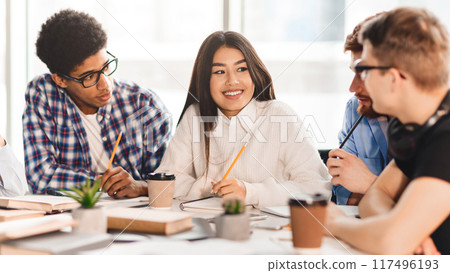 Happy multiracial college students studying with books in library, preparing together for final exams 117496193