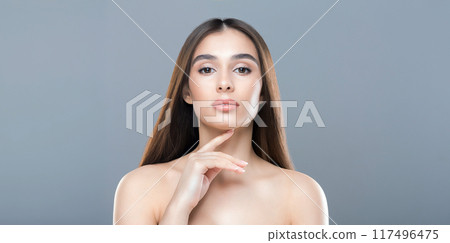 A woman with long brown hair is striking a pose for the camera. She stands confidently, gazing directly at the lens with a slight smile. Her hair cascades down her shoulders A woman with long brown hair is striking a pose for the camera. She stands confidently, gazing directly at the lens with a slight smile. Her hair cascades down her shoulders 117496475