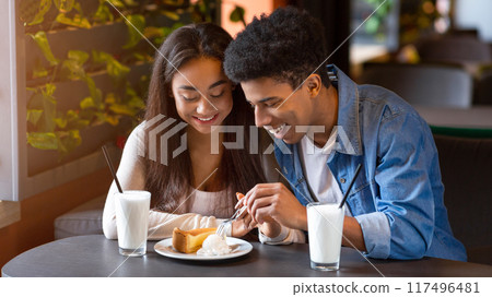African American young guy and girl are seated at a table in a restaurant, enjoying a meal together, focused on their plates, engaged in conversation, and surrounded by other diners and restaurant African American young guy and girl are seated at a table in a restaurant, enjoying a meal together, focused on their plates, engaged in conversation, and surrounded by other diners and restaurant 117496481
