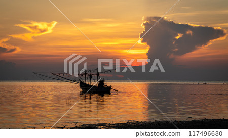 Boat grounded on beach as sunset on the horizon, casting a warm afterglow Boat grounded on beach as sunset on the horizon, casting a warm afterglow 117496680