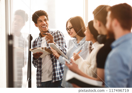 Students writing tasks on whiteboard in class, laughing with classmates Students writing tasks on whiteboard in class, laughing with classmates 117496719