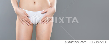 A woman is posing in white underwear with her hands near her hips. The background is plain grey, and the image seems well-lit, panorama with copy space A woman is posing in white underwear with her hands near her hips. The background is plain grey, and the image seems well-lit, panorama with copy space 117497211
