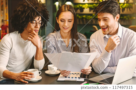 Millennial business team discussing project in cafe, reading contract terms and conditions during business lunch, free space Millennial business team discussing project in cafe, reading contract terms and conditions during business lunch, free space 117497315