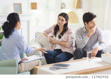 A woman psychologist offers guidance to a young couple, helping them navigate their relationship issues in a peaceful, confidential therapy environment. A woman psychologist offers guidance to a young couple, helping them navigate their relationship issues in a peaceful, confidential therapy environment. 117497439