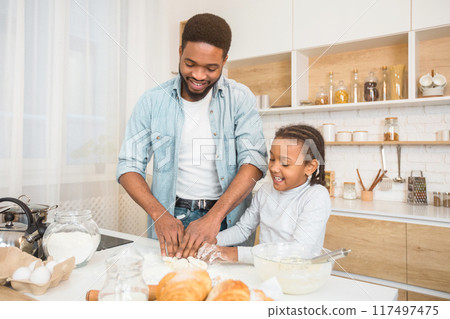 Happy african american father and daughter kneading dough for pastry at home kitchen, copy space Happy african american father and daughter kneading dough for pastry at home kitchen, copy space 117497475