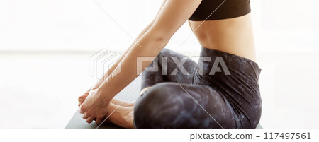 Cropped of woman is seated on a yoga mat in a gym, stretching and performing yoga exercises during her morning workout, wearing athletic wea, emphasizing flexibility and mindfulness, panorama Cropped of woman is seated on a yoga mat in a gym, stretching and performing yoga exercises during her morning workout, wearing athletic wea, emphasizing flexibility and mindfulness, panorama 117497561