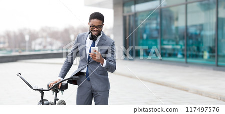 African American man is on his bicycle in an urban area, engaged with his phone. The mood is fast-paced and professional, highlighting a modern city lifestyle. 117497576