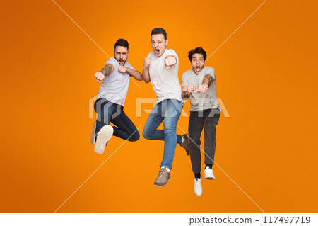 Three european guys showcase energetic friendship with a mid-air jump, expressing joy and carefree mates Three european guys showcase energetic friendship with a mid-air jump, expressing joy and carefree mates 117497719