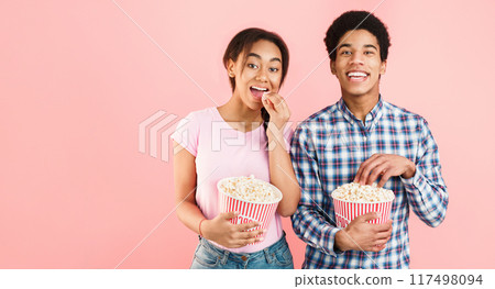 African-american students eating popcorn, watching movie on pink background 117498094