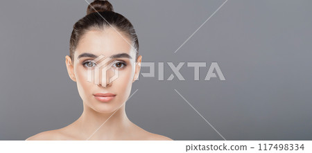 A close-up of a woman face featuring a neatly done bun in the center of her hair. Her features are visible, and the focus is on the hairstyle, panorama with copy space 117498334