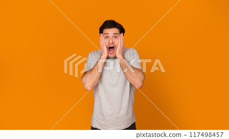 Wow. Shocked men with open mouth looking at camera over orange background Wow. Shocked men with open mouth looking at camera over orange background 117498457