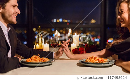Romantic couple touching hands and smiling while having dating in restaurant. Happy evening together concept 117498624