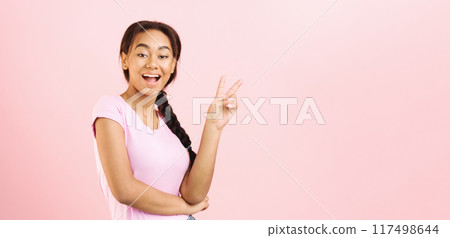 A young African American girl is making a peace sign gesture. She smiles as she holds up her fingers in the iconic symbol of peace and harmony, copy space 117498644