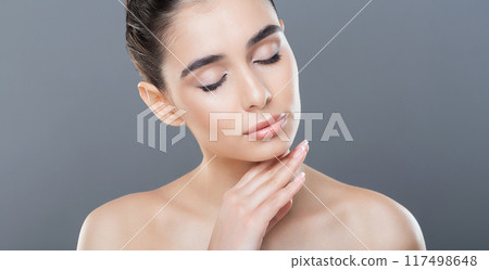 A woman with her hands resting on her face, expressing emotions or deep in thought. She appears to be contemplative or distressed, with a thoughtful expression on her face. 117498648