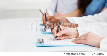 Medical seminar. Doctors writing notes at conference in hospital, closeup Medical seminar. Doctors writing notes at conference in hospital, closeup 117498887