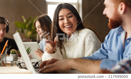 College students using laptop in library, studying for school assignment, discussing together 117499000