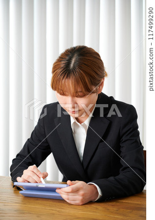 穿著西裝的女人在家操作平板電腦 穿著西裝的女人在家操作平板電腦 117499290