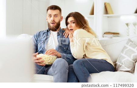 Couple Watching Horror Movie And Eating Popcorn, Spending Weekend At Home Couple Watching Horror Movie And Eating Popcorn, Spending Weekend At Home 117499320