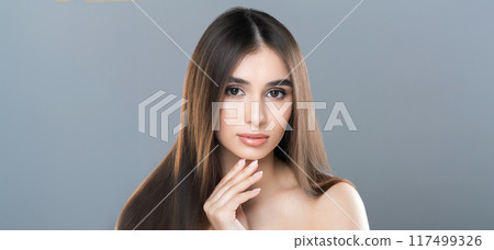 A woman with long hair is striking a pose for a photograph. She is looking directly at the camera with a confident expression, showcasing her flowing hair. The background is non-descript 117499326