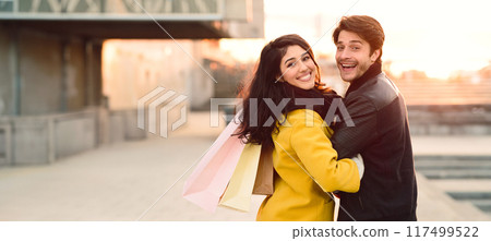 A man and a woman embracing in front of a tall building, showing affection and connection. 117499522