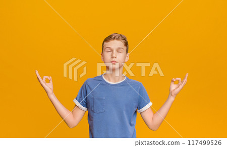 Zen, meditation, balance and peace concept. Portrait of cute little boy holding his fingers in mudra gesture, meditating with closed eyes, orange background Zen, meditation, balance and peace concept. Portrait of cute little boy holding his fingers in mudra gesture, meditating with closed eyes, orange background 117499526