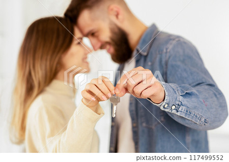 Loving Couple Showing Keys From Their New House, Newlyweds Touching Foreheads, Side View Loving Couple Showing Keys From Their New House, Newlyweds Touching Foreheads, Side View 117499552