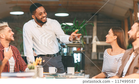 Enthusiastic team members participate in a lively discussion during a friendly office meeting in a modern workspace. Enthusiastic team members participate in a lively discussion during a friendly office meeting in a modern workspace. 117499587