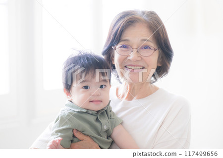 抱著孫子的老婦人看著相機 抱著孫子的老婦人看著相機 117499656