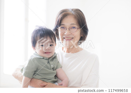 Senior woman holding her grandchild, looking at camera 117499658