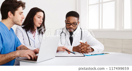 Medical Team Discussing Reports, Using Laptop in Meeting Room 117499659
