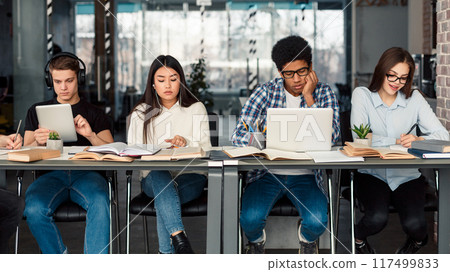 Students using different gadgets studying in university library and preparing for exams Students using different gadgets studying in university library and preparing for exams 117499833