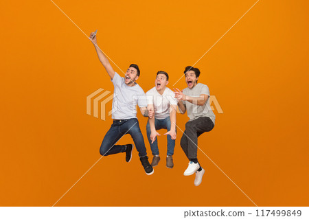 Fooling together. Men taking selfie when jumping on orange studio background 117499849