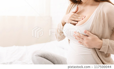 Young pregnant woman having painful feelings in breast, massaging herself, panorama with free space 117500044