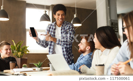Look here. Guy showing phone to student friends, doing research in library together 117500061