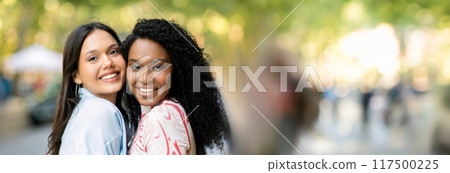 Friendship Concept. Portrait Of Two Happy Girlfriends Posing Outdoors, Cheerful Multiethnic Women Embracing And Smiling At Camera, Joyful Besties Enjoying Walk In City, Closeup Shot, Copy Space Friendship Concept. Portrait Of Two Happy Girlfriends Posing Outdoors, Cheerful Multiethnic Women Embracing And Smiling At Camera, Joyful Besties Enjoying Walk In City, Closeup Shot, Copy Space 117500225
