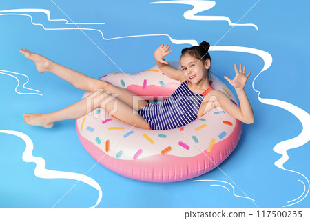 A young girl, wearing a swimsuit, is lying on an inflatable donut float in illustrated swimming pool. The girl seems relaxed and content as she floats on the colorful donut. 117500235