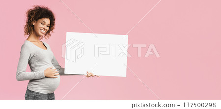 Black pregnant woman showing blank advertising board over pink studio background, free space Black pregnant woman showing blank advertising board over pink studio background, free space 117500298