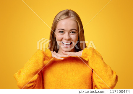 Youth concept. Portrait of happy teenage girl leaning chin on her palms, orange background with copy space Youth concept. Portrait of happy teenage girl leaning chin on her palms, orange background with copy space 117500474