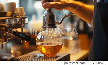 A barista skillfully brews coffee using a siphon in a warm cafe, showcasing the unique process and aroma as the drink caramelizes. 117500529