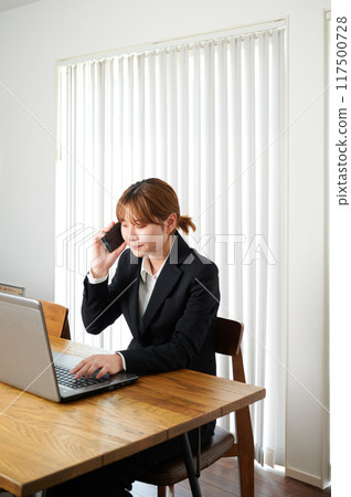 Woman talking on smartphone, suit, working from home 117500728