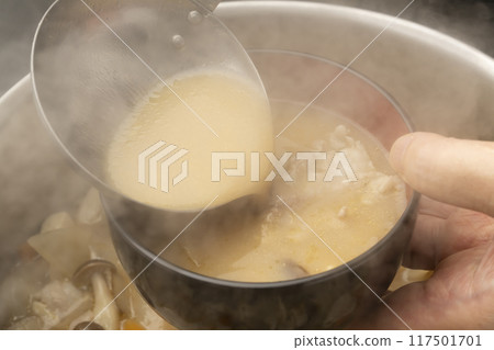 豬肉湯:用湯匙將豬肉湯倒入碗中。 豬肉湯:用湯匙將豬肉湯倒入碗中。 117501701