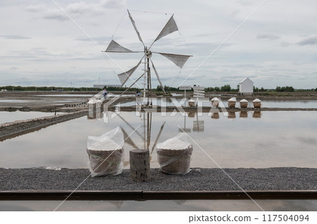 Salt in basket at evaporation pond farm with windmill, Samut Songkhram 117504094