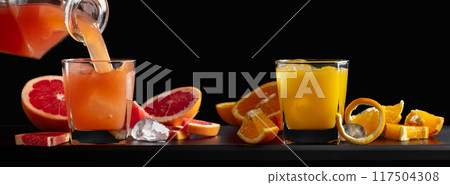 Glasses of grapefruit and orange juice with ice on a black background. 117504308