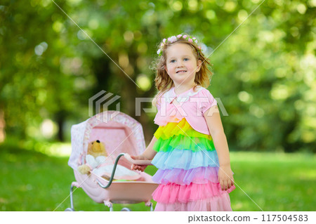 Little girl pushing a toy stoller wth doll Little girl pushing a toy stoller wth doll 117504583
