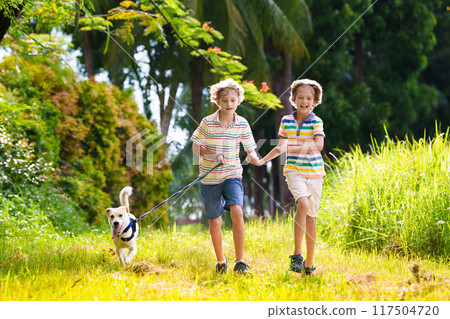 Kids play with dog. Children and puppy run in park 117504720