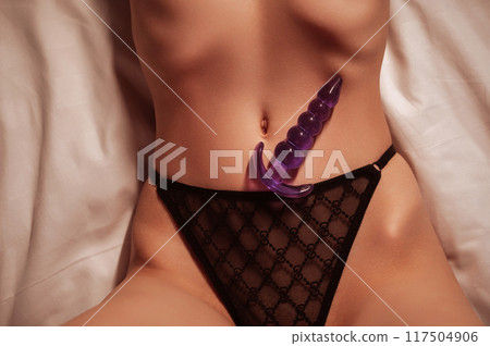 silicone butt anal plug lies on the sexy body of a woman girl in panties on the bed in bedroom. Female sex toys for anal sex and orgasm silicone butt anal plug lies on the sexy body of a woman girl in panties on the bed in bedroom. Female sex toys for anal sex and orgasm 117504906