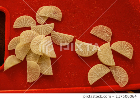 Cut pieces of radishes with visible veins, arranged in the form of a mother and child, reaching out to each other with their hands. Abstract symbols, family values, parenthood, motherhood 117506064