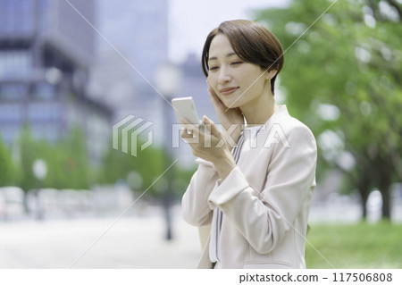 中年婦女在公園裡看著一個粉盒 中年婦女在公園裡看著一個粉盒 117506808