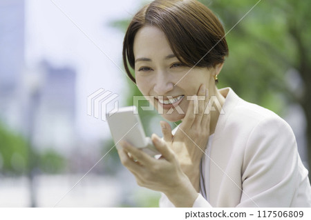 微笑的中年婦女看著公園裡的一個粉盒 117506809